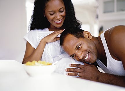 close-up of a man resting his head on his pregnant wife's stomach; smiling